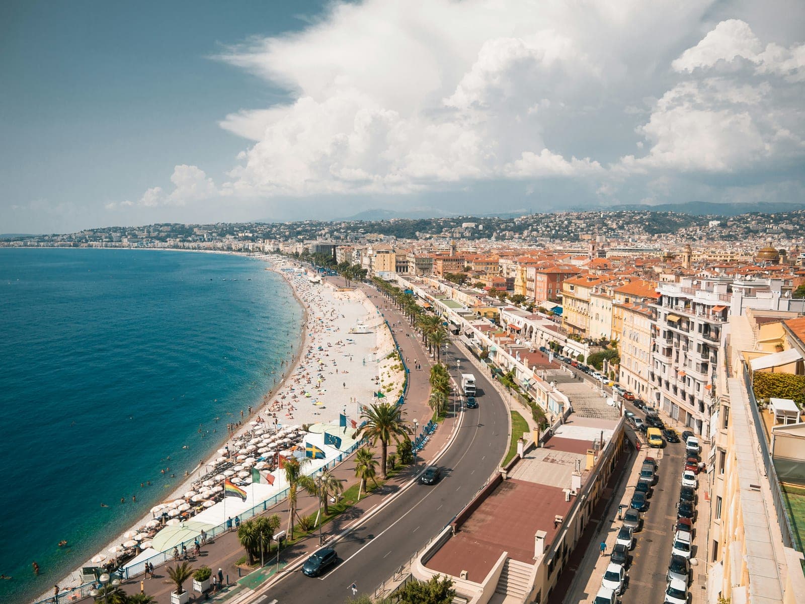 Seaside promenade and beach lined with palms beside a coastal city