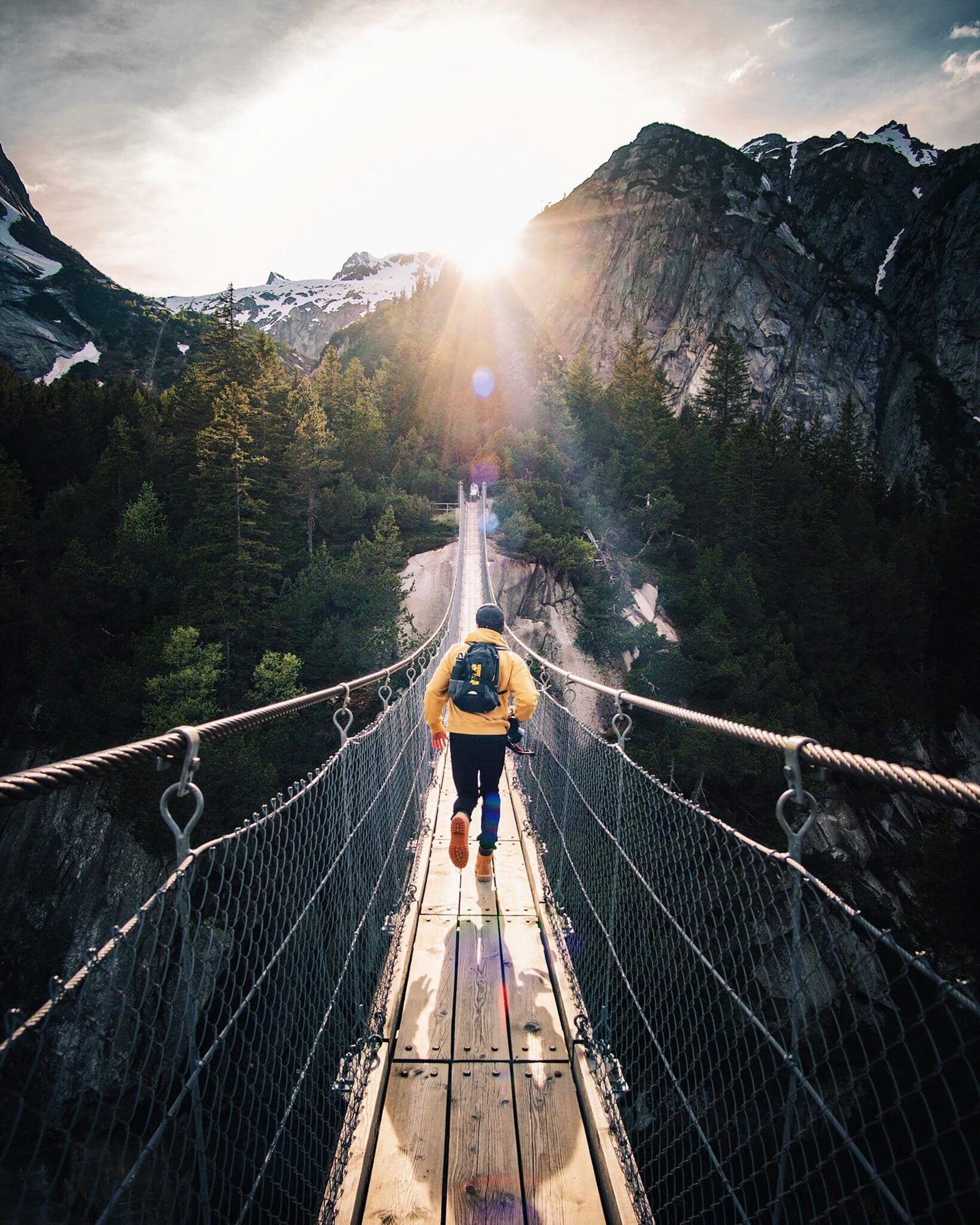 Hiker crossing a suspension bridge in a mountain forest
