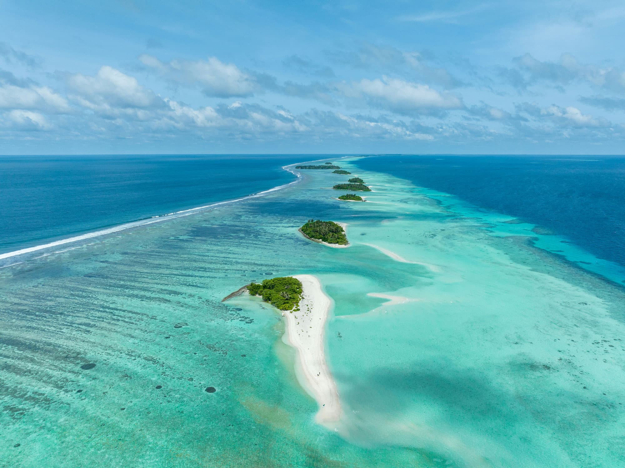 Aerial view of a turquoise atoll with sandbars and small islands